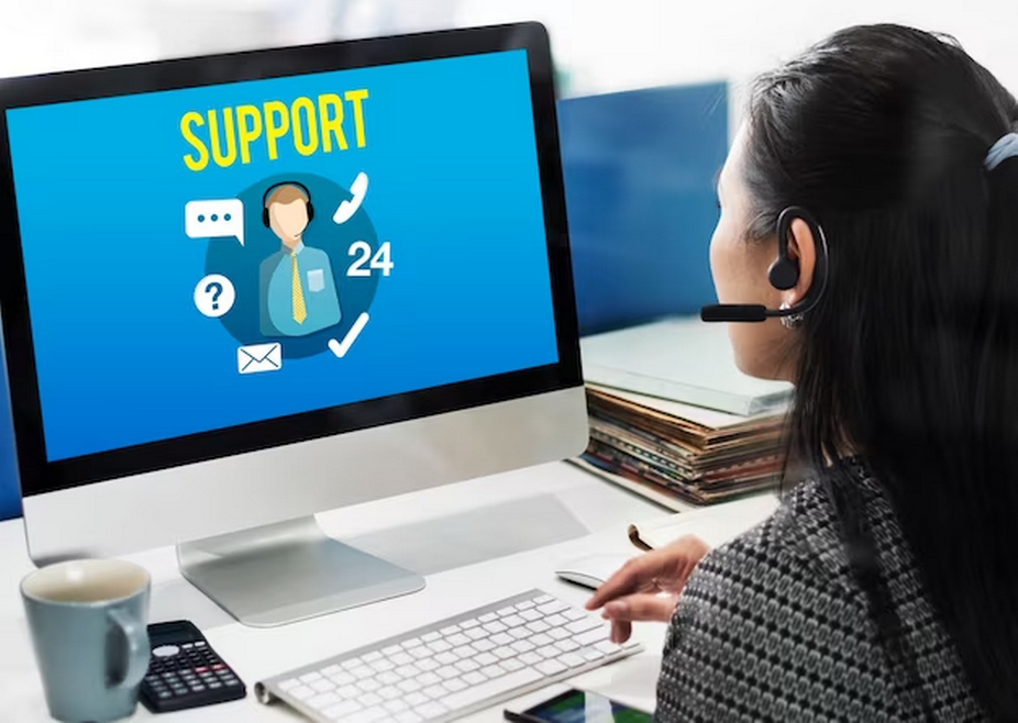 A customer support agent with a headset in front of a computer.